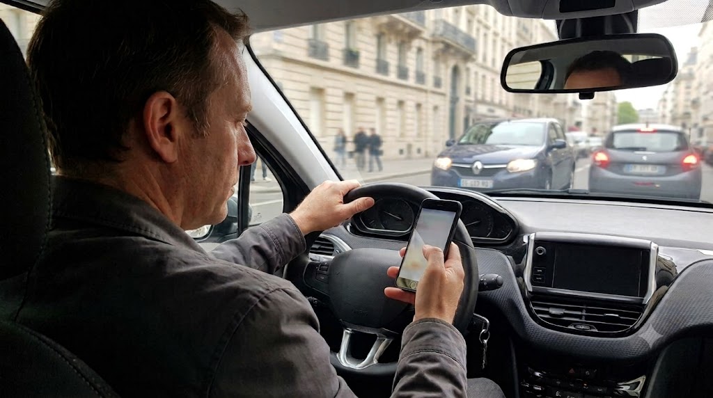 Un conducteur consulte son téléphone au volant