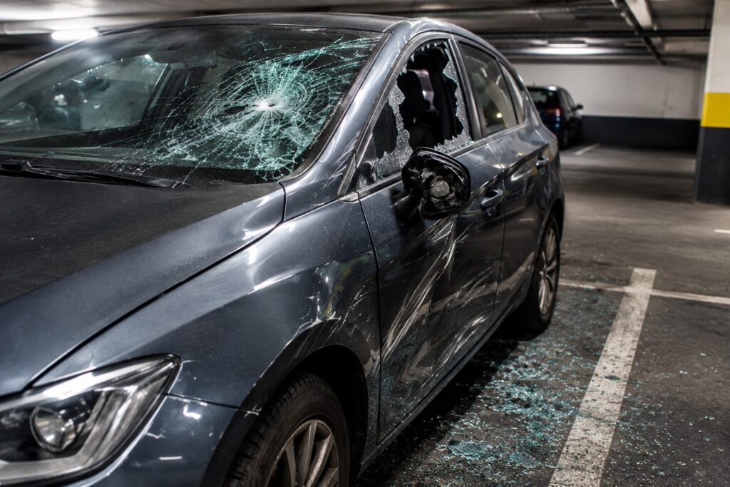 Voiture vandalisée avec les vitres brisées sur un parking couvert